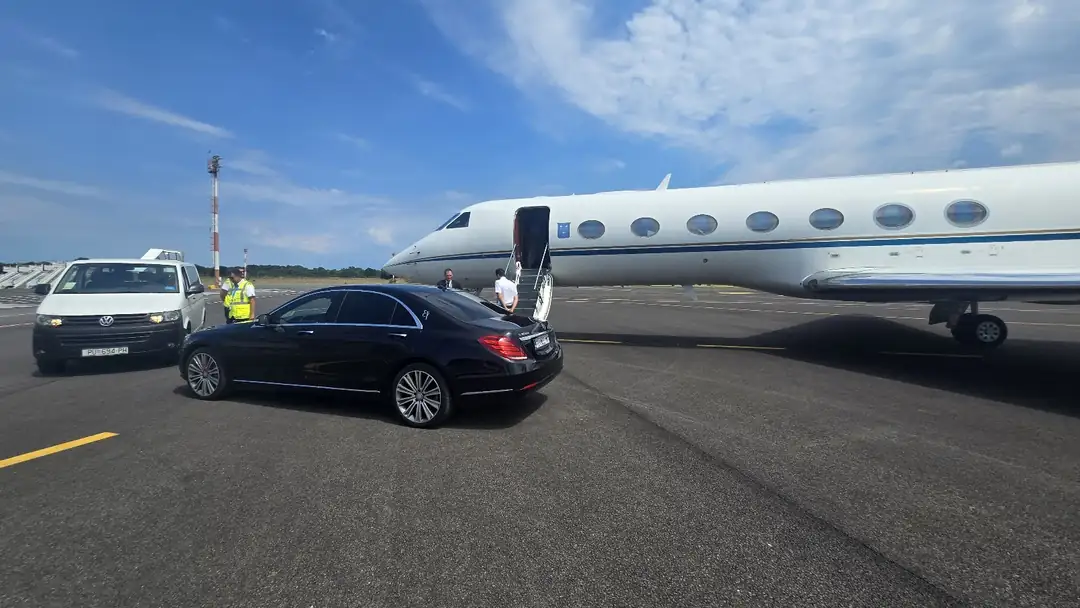 Black Mercedes S-Class of Taxi Transfers Umag waiting next to a private jet on the airport apron