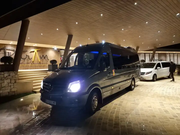 Mercedes Sprinter minibus at a hotel entrance at night