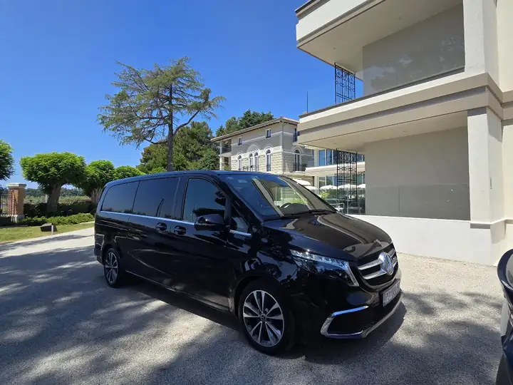 Black Mercedes V-Class van in front of a hotel